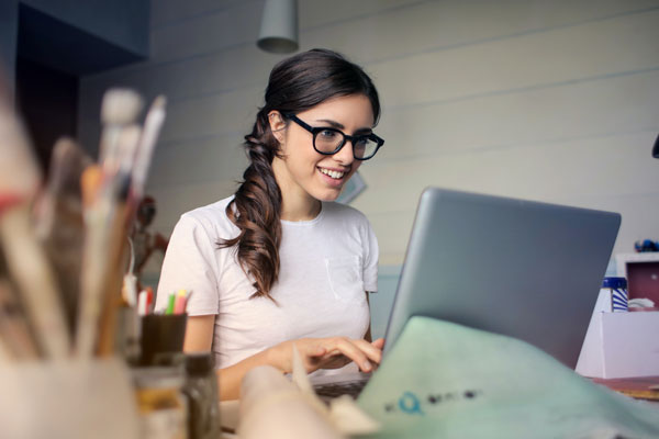 Girl smiling and wearing glasses, searcing on her laptop